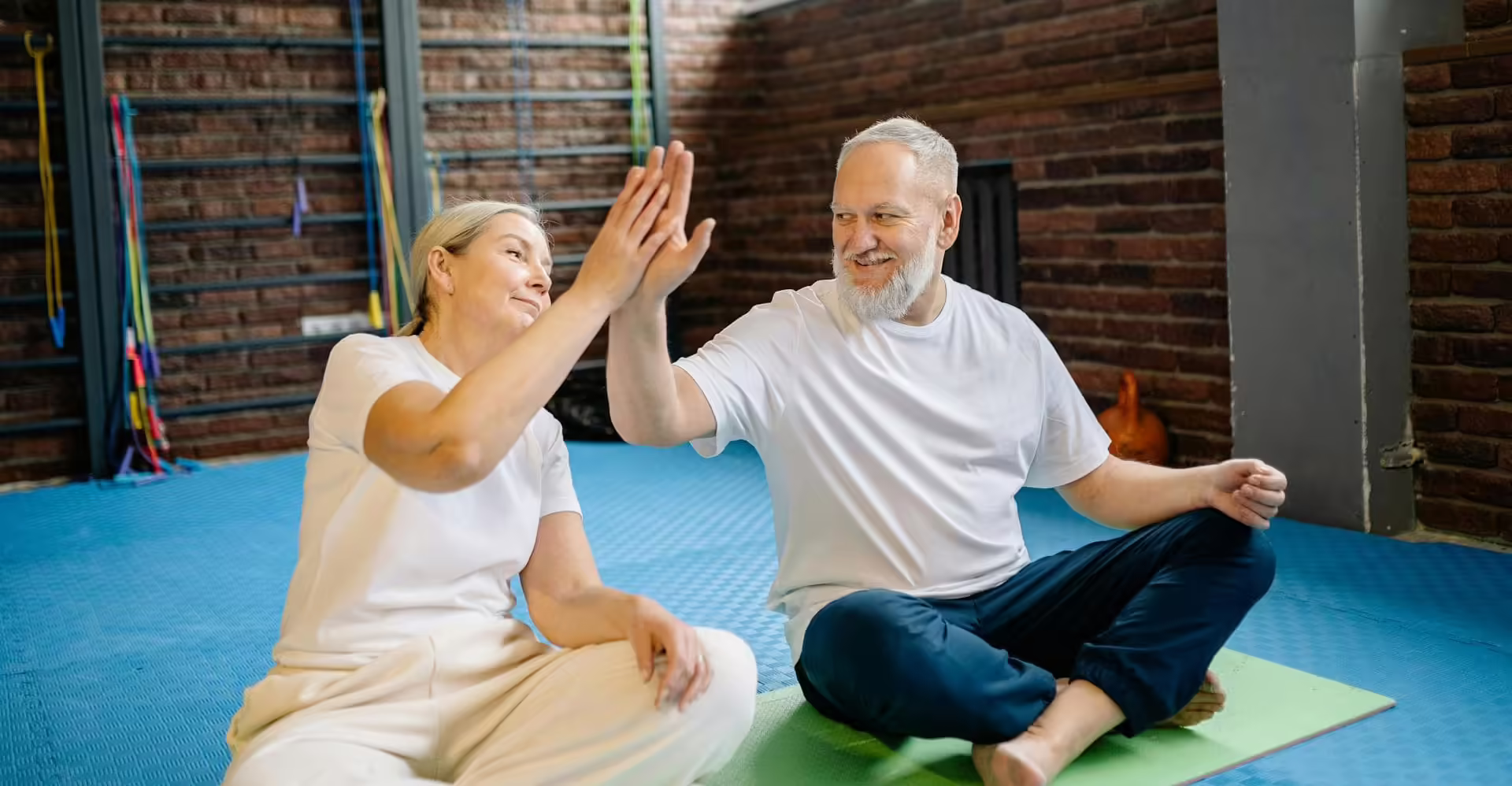 Senior man and woman high-fiving during a wellness activity at Artisan Heights.