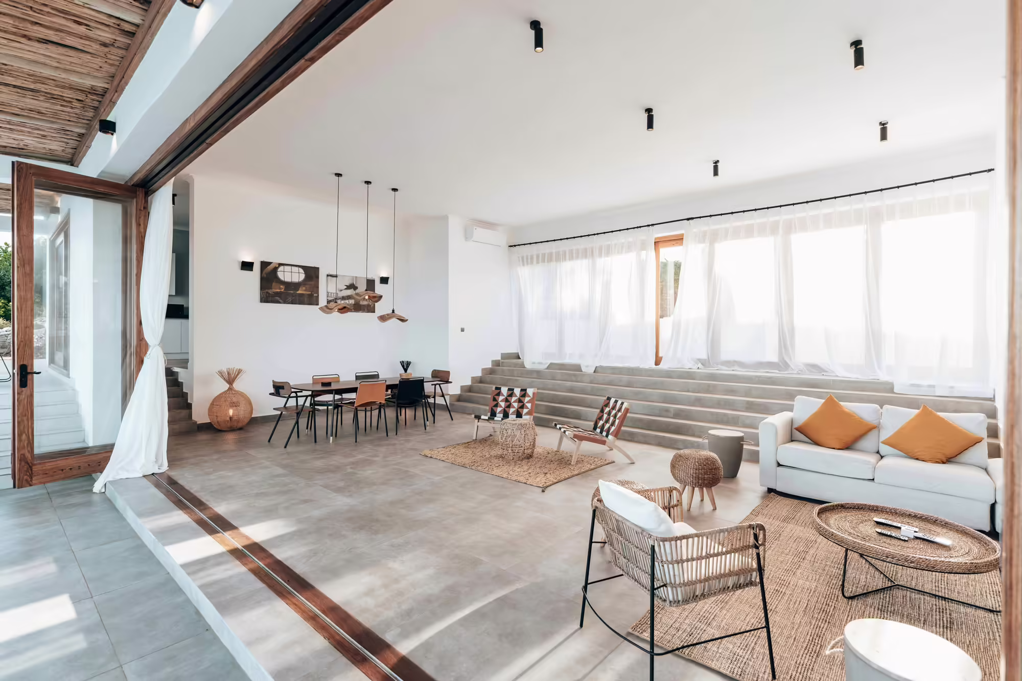 A modern, open-concept living space with large windows, natural light, and stylish furniture.