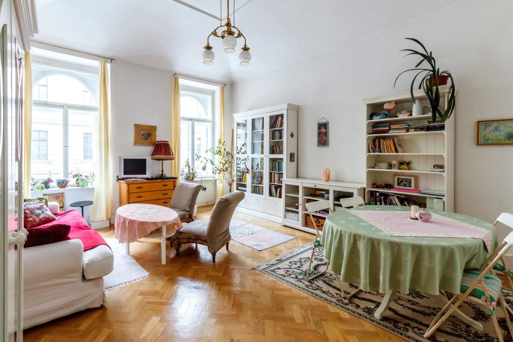 A charming, well-lit apartment with cozy furnishings, vintage decor, and natural light streaming through large windows.